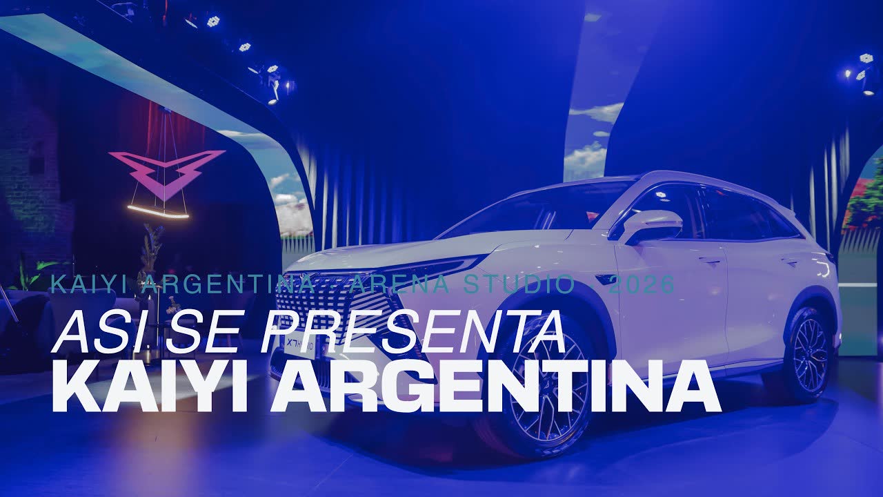 Foto del salón el día del evento, con el auto blanco bajo la luz azul